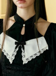 a woman with long hair wearing a black and white dress, collared shirt and necklace