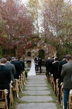 a bride and groom standing at the end of their wedding ceremony in front of an outdoor stone fireplace