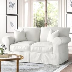 a living room with white furniture and pictures on the wall