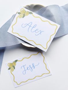 two place cards with lemons on them are next to some blue and white ribbons