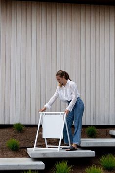 a woman is standing on some steps with a chair in front of her and plants