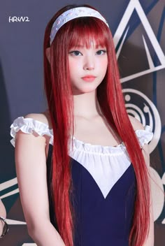 a woman with long red hair wearing a blue dress and headband is standing in front of a wall