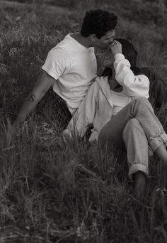 black and white photograph of a man sitting in the grass talking on his cell phone