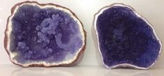 two pieces of purple rock sitting on top of a white counter next to each other