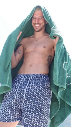 a shirtless man standing under a green towel