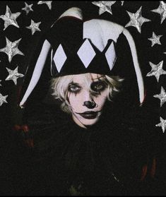 a man with white makeup and clown make - up on his face, standing in front of stars