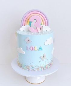 a birthday cake decorated with rainbows and clouds