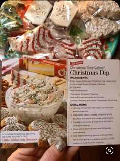 someone holding up a christmas dip recipe in front of candy canes and other treats