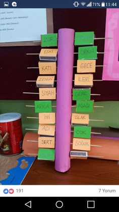 a stack of books sitting on top of a wooden table next to a purple pole