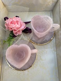 two pink roses sitting on top of plates in a box