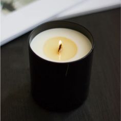 a lit candle sitting on top of a black table next to a white box with an open lid