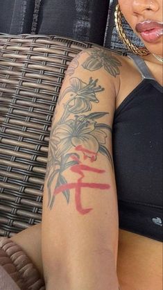 a woman with a tattoo on her arm sitting in front of a wicker chair