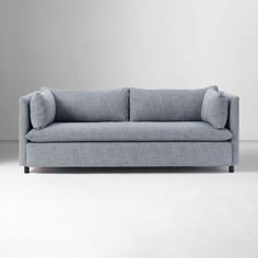 a blue couch sitting on top of a white floor next to a gray wall in an empty room