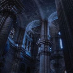 the interior of an old church with columns and stained glass windows, all lit up at night