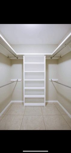 an empty walk in closet with white shelves