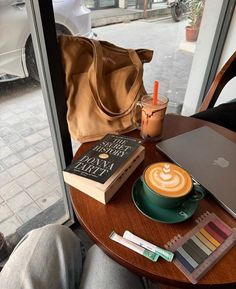 there is a cup of coffee on the table next to some books and a laptop