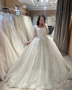 a woman in a wedding dress is taking a selfie with her cell phone while looking at dresses