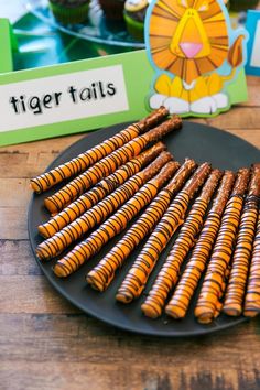 tiger tails are arranged on a black plate next to cupcakes and other treats