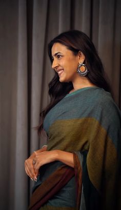 a woman in a green and brown sari with earrings on her head, looking off to the side