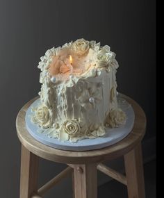 a white cake sitting on top of a wooden table with a lit candle in it