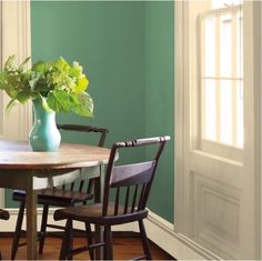 a dining room table with chairs and a vase filled with flowers on top of it