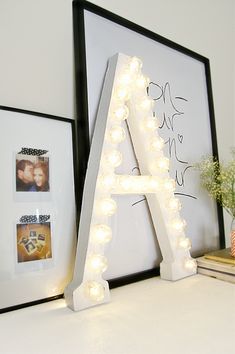 a light up letter sitting on top of a desk next to a vase with flowers