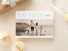 a christmas card with an image of a family walking on the beach in front of it