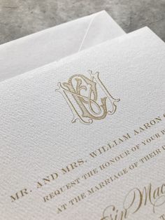 an elegant lettered wedding card is displayed on a marble surface with gold foiling