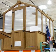 a large wooden building sitting on top of a pallet in a warehouse next to an american flag