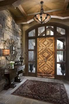 the entrance to a home with stone walls and an ornate glass paneled entry door