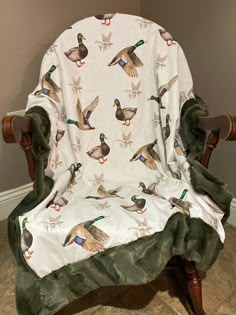 a rocking chair with ducks on it and green velvet seat cover over the armrests