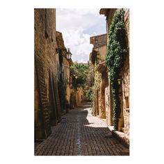 an alley way with stone buildings and ivy growing on the walls, surrounded by cobblestones