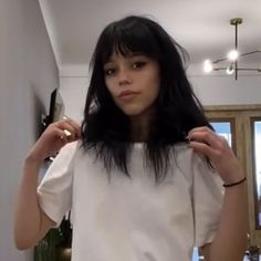 a woman with long black hair standing in a room