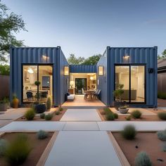 a couple of blue shipping containers sitting in the middle of a yard with gravel and plants