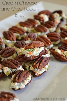 some pecans are on a white plate with cream cheese and olive pecan bites