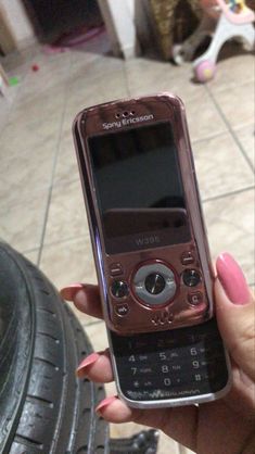 a person holding up a cell phone in their hand on the floor next to some tires