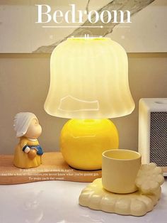 a yellow lamp sitting on top of a table next to a cup