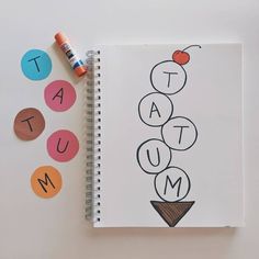 an open notebook with the word tat - tum on it next to some crayons