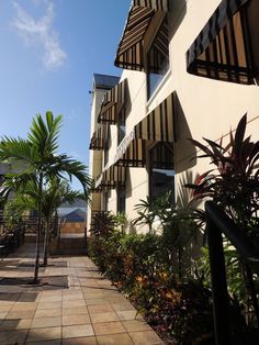 an apartment building with many balconies and palm trees on the sidewalk next to it