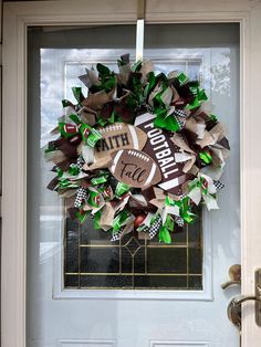 a football wreath is hung on the front door with green and brown ribbon around it