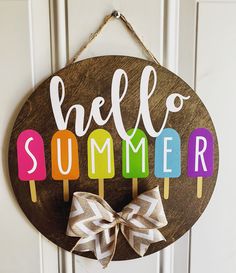 a wooden sign that says hello summer with popsicles on it and a bow hanging from the front door