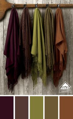 four different colors of towels hanging on a rack with a wooden paddle in the background