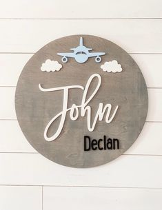 a wooden sign that says john dechan with an airplane in the sky above it