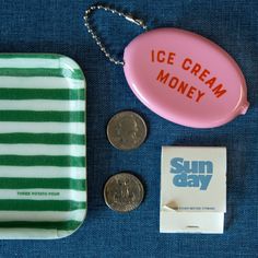 an ice cream money box, coin and keychain on a blue cloth with the words sun day written on it