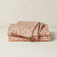 an orange and pink floral print sheet set on top of a white surface with the sheets folded down