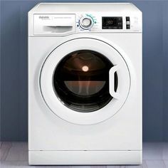 a white washer sitting on top of a wooden floor next to a blue wall