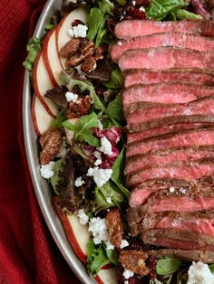 an apple and beef salad with goat cheese on top is served in a silver bowl