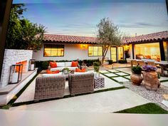 an outdoor living area with couches, tables and chairs in front of a house