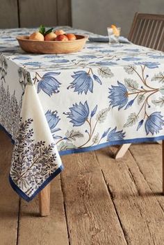 a bowl of fruit sitting on top of a table covered in blue and white cloth