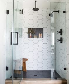 a bathroom with a glass shower door and wooden stool next to the shower stall area